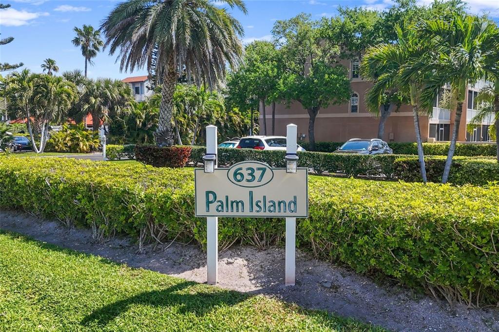 A sign reading 637 Palm Island stands in front of a hedge and palm trees — 637 PINELLAS BAYWAY S UNIT 301, TIERRA VERDE, FL