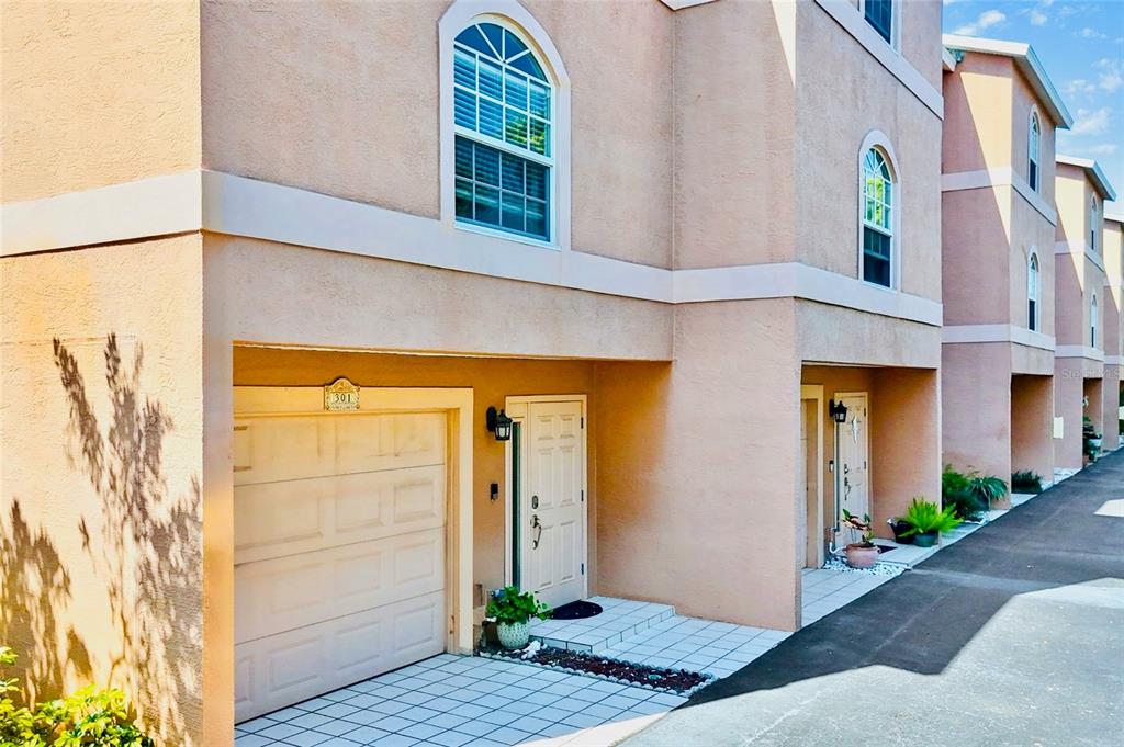 A multi-story townhouse exterior features a tan stucco facade, arched windows, and a ground-level garage — 637 PINELLAS BAYWAY S UNIT 301, TIERRA VERDE, FL