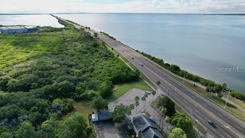 An aerial view shows a building next to a highway running along a large body of water — 14 SEAGRAPE CIRCLE, CLEARWATER, FL