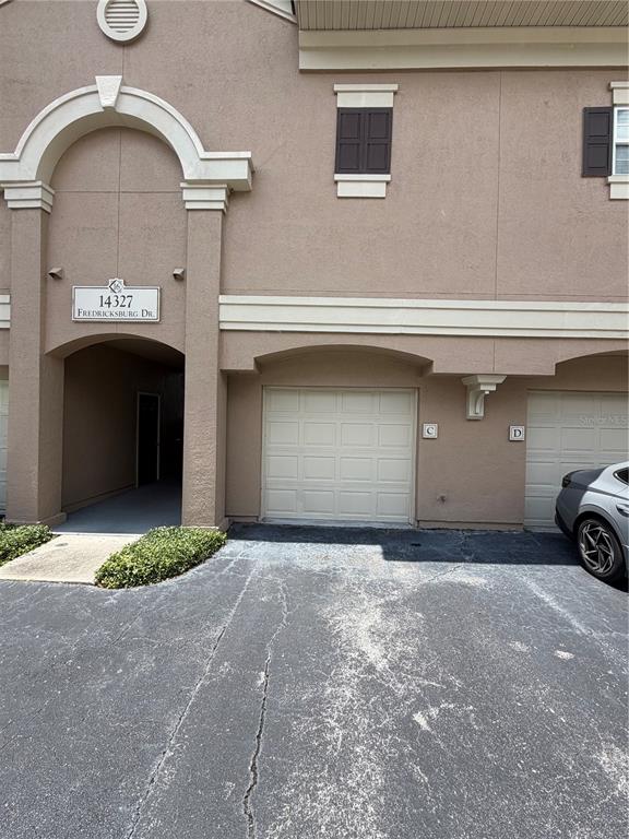 The exterior of a multi-unit building features a covered entryway and two garage doors — 14327 FREDRICKSBURG DRIVE UNIT 1601, ORLANDO, FL