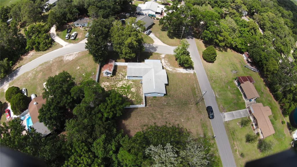 An aerial view shows a residential property with a light-colored house, shed, and surrounding trees — 26408 ROLLING ACRES DRIVE, BROOKSVILLE, FL