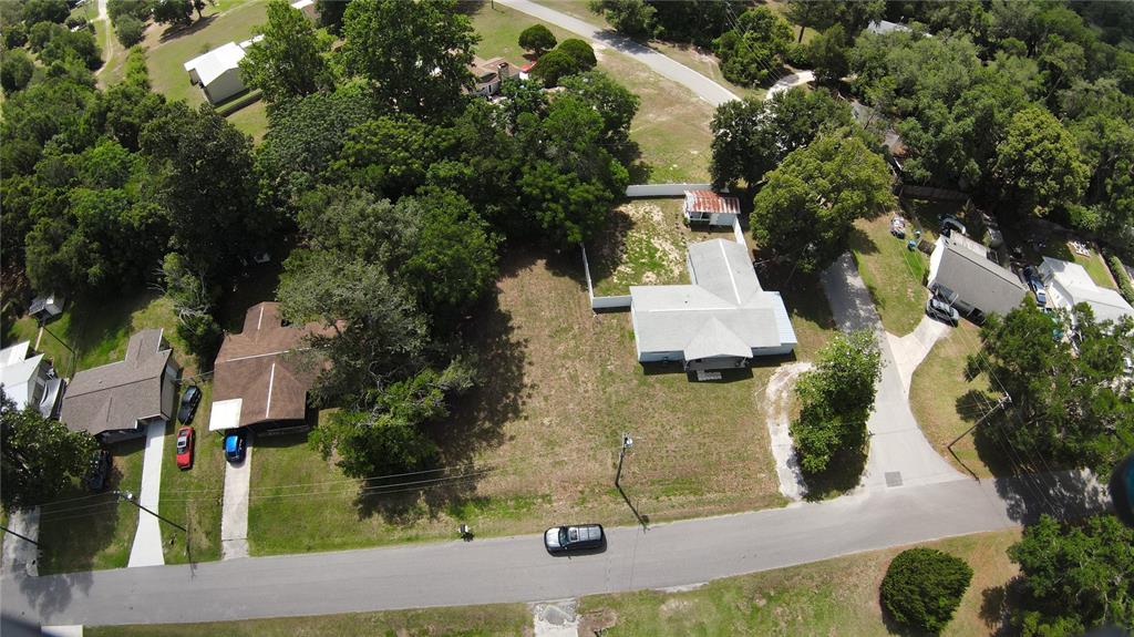 An aerial view shows a residential lot with two houses separated by an open yard — 26408 ROLLING ACRES DRIVE, BROOKSVILLE, FL