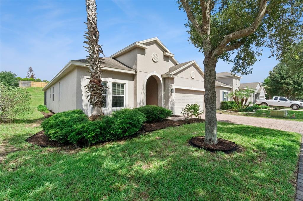 A single-story beige house with a two-car garage and a front yard with trees — 457 BRIDGEFORD CROSSING BOULEVARD, DAVENPORT, FL