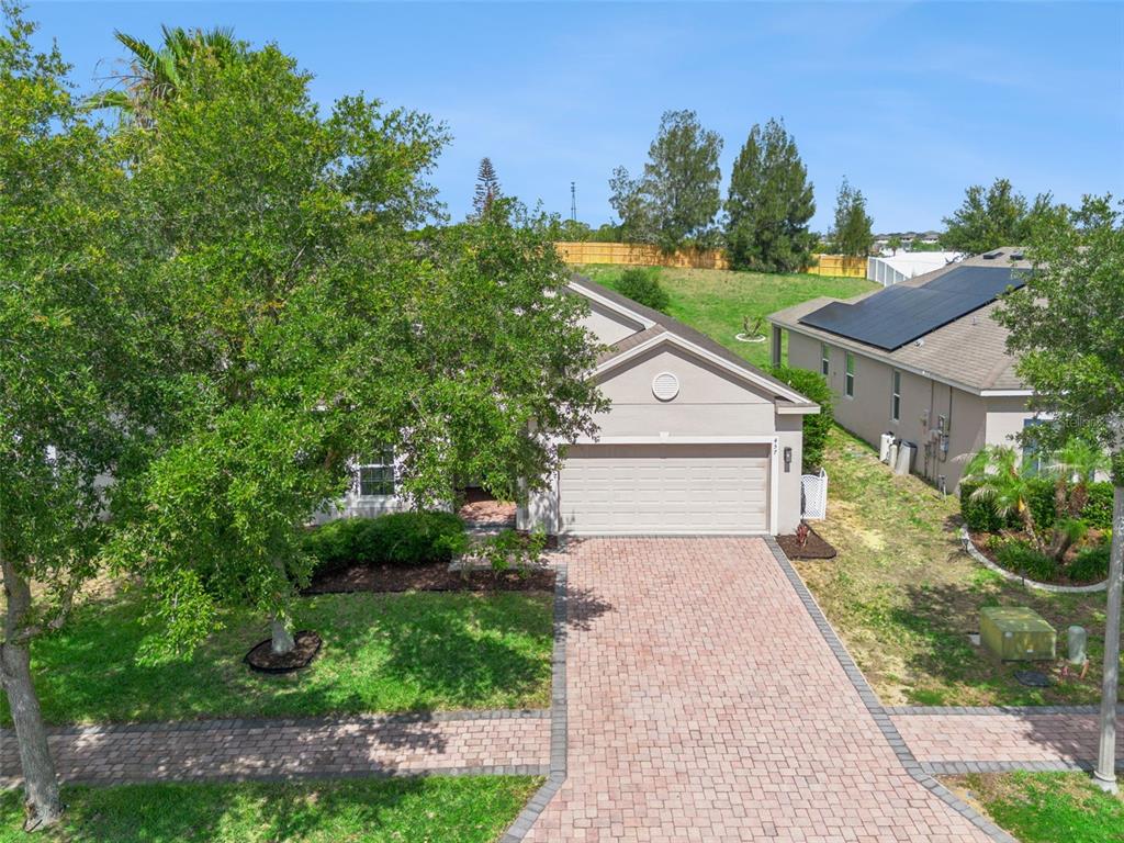 A single-story suburban house with a paver driveway and a large tree in the front yard — 457 BRIDGEFORD CROSSING BOULEVARD, DAVENPORT, FL