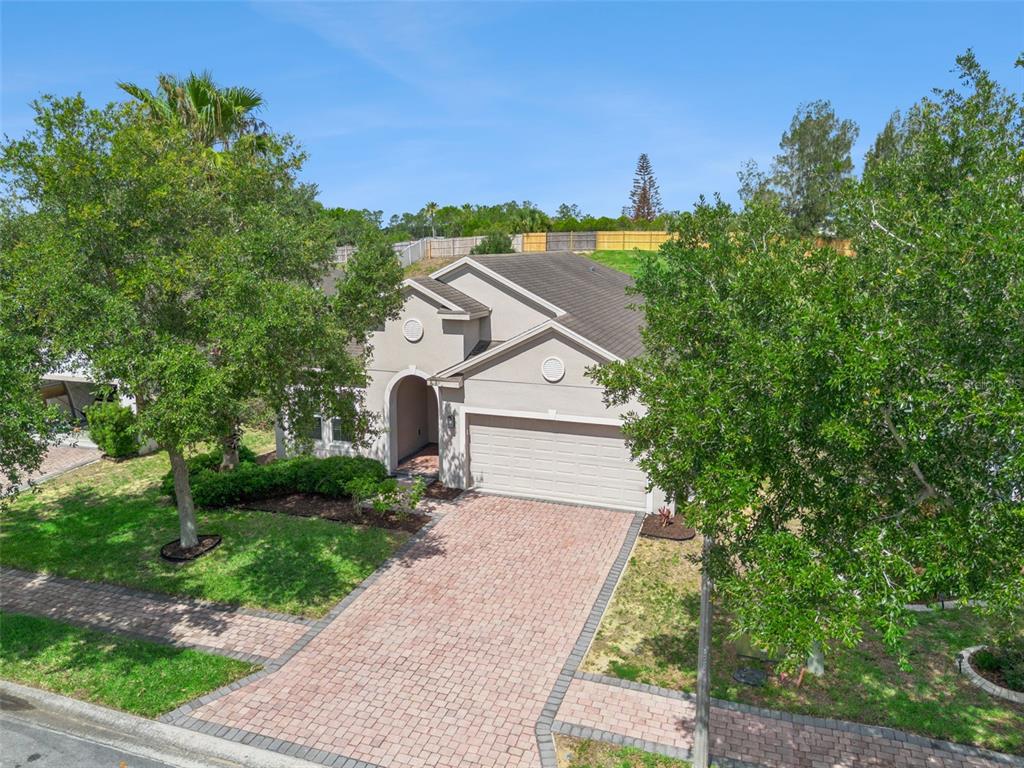 A single-story house with a beige stucco exterior, a two-car garage, and a paver driveway — 457 BRIDGEFORD CROSSING BOULEVARD, DAVENPORT, FL