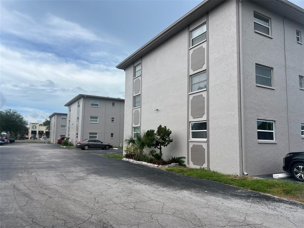 Exterior view of multi-story apartment buildings with gray stucco walls and a paved parking lot — 8701 4TH STREET N UNIT 105, ST PETERSBURG, FL