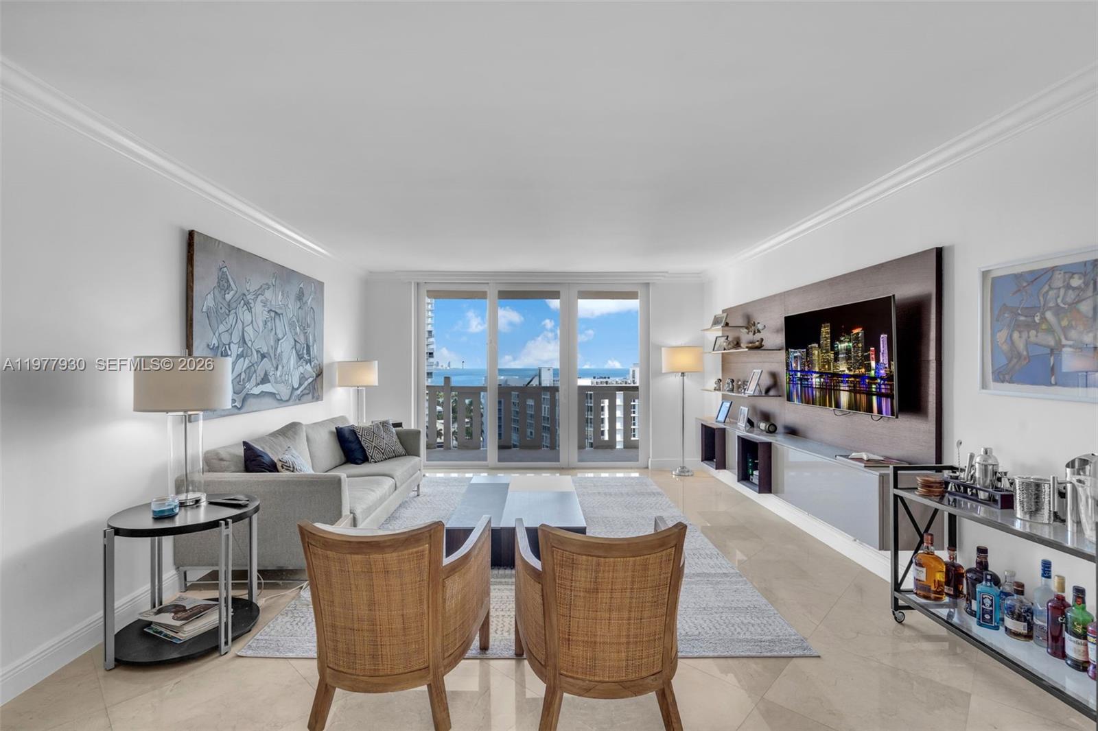 A living room features a grey sofa, two rattan chairs, and a wall-mounted television — 1121 Crandon Blvd # E1203, Key Biscayne FL 33149, KEY BISCAYNE, FL