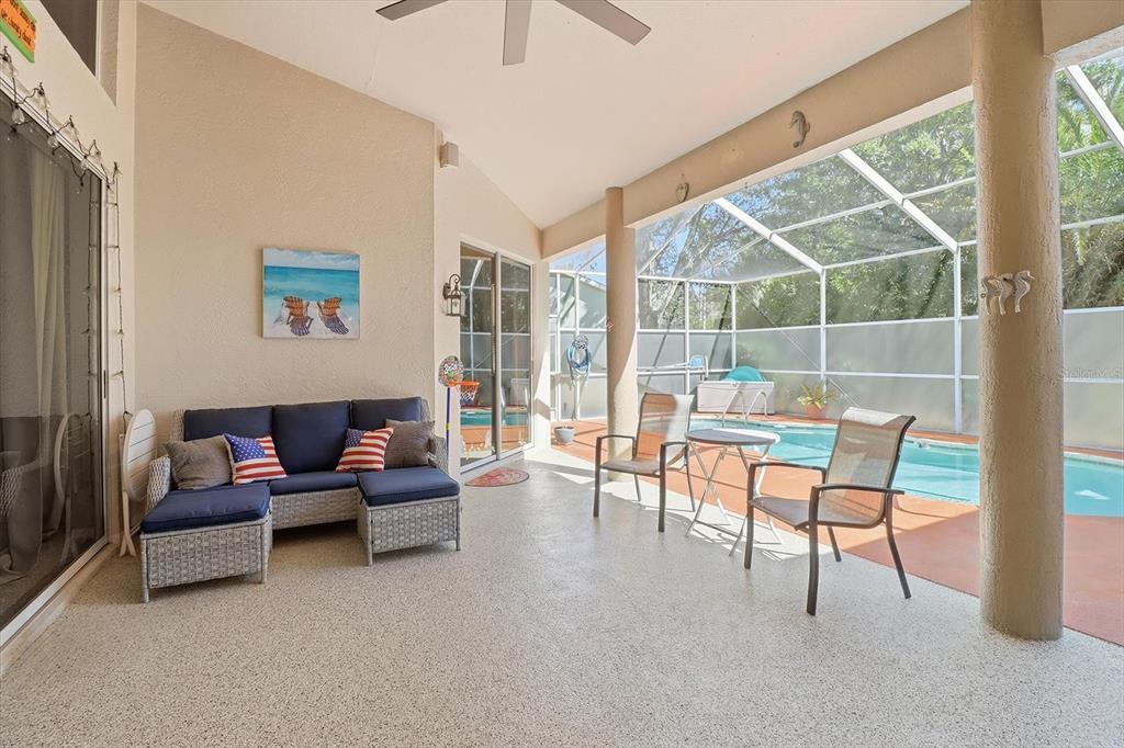 A covered patio features a blue sectional sofa, two chairs, and a screened-in swimming pool — 5628 W HUNTERS RIDGE CIRCLE, LECANTO, FL