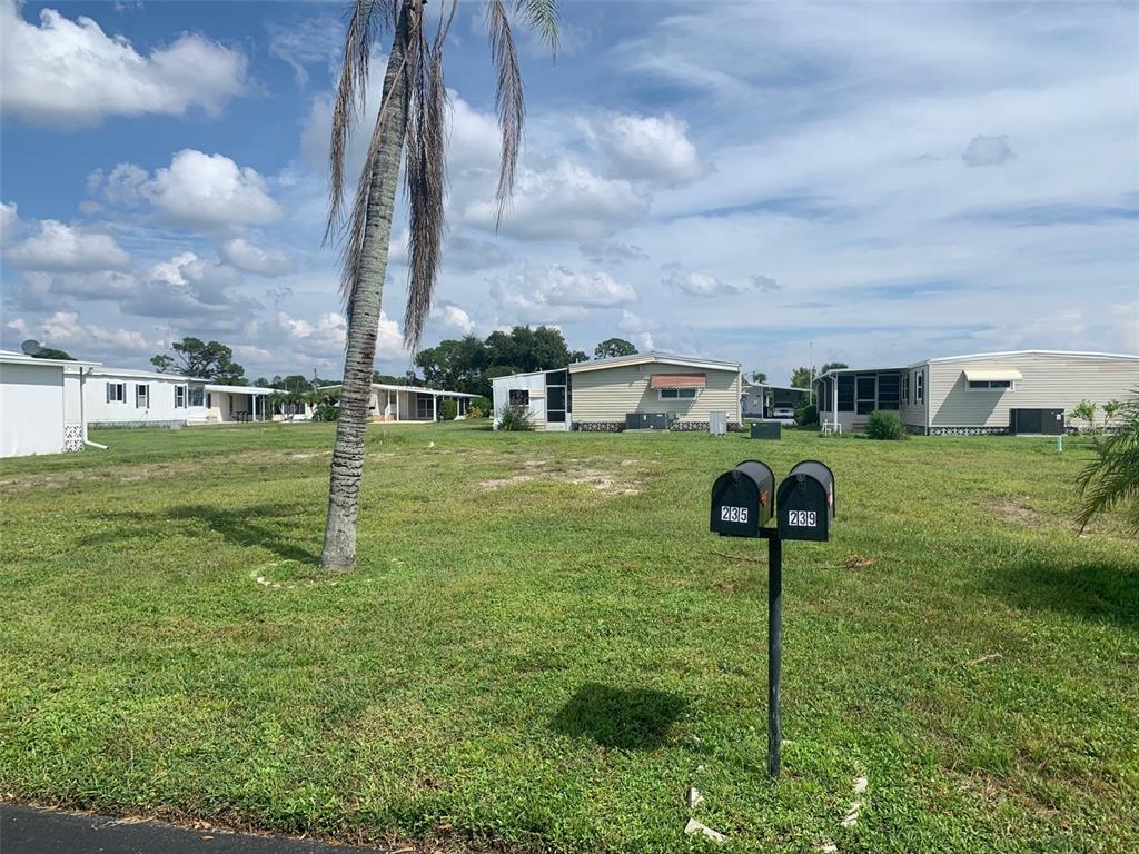 A grassy lot with two mailboxes stands in front of several manufactured homes — 235 ESTRADA, NORTH PORT, FL