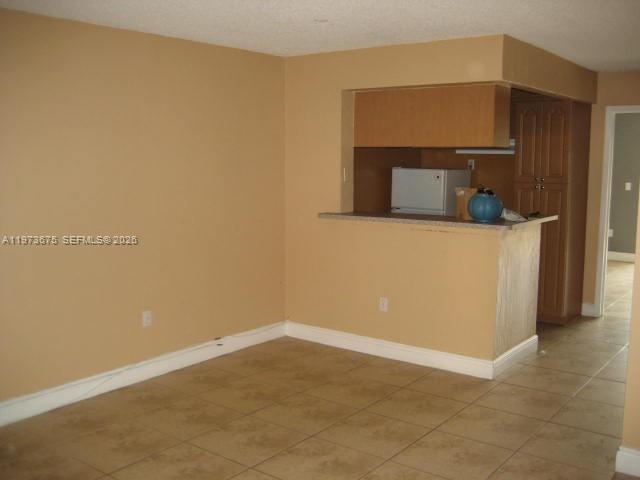 An interior view shows a room with beige walls, tile flooring, and a kitchen pass-through — 10832 N KENDALL DR # 6, Miami FL 33176, MIAMI, FL