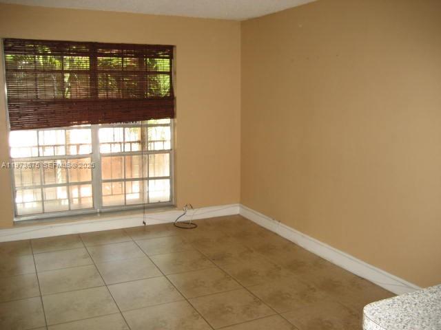 An empty room features tan walls, light-colored tile flooring, and a window with bamboo blinds — 10832 N KENDALL DR # 6, Miami FL 33176, MIAMI, FL