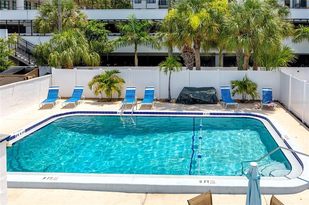 A rectangular swimming pool with lounge chairs sits in a fenced outdoor patio area — 4340 37TH STREET S UNIT 6, ST PETERSBURG, FL