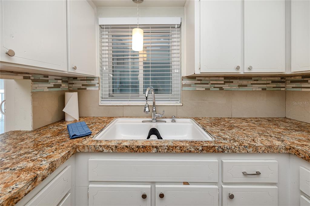 A kitchen sink area features white cabinets, granite countertops, and a tiled backsplash — 4340 37TH STREET S UNIT 6, ST PETERSBURG, FL