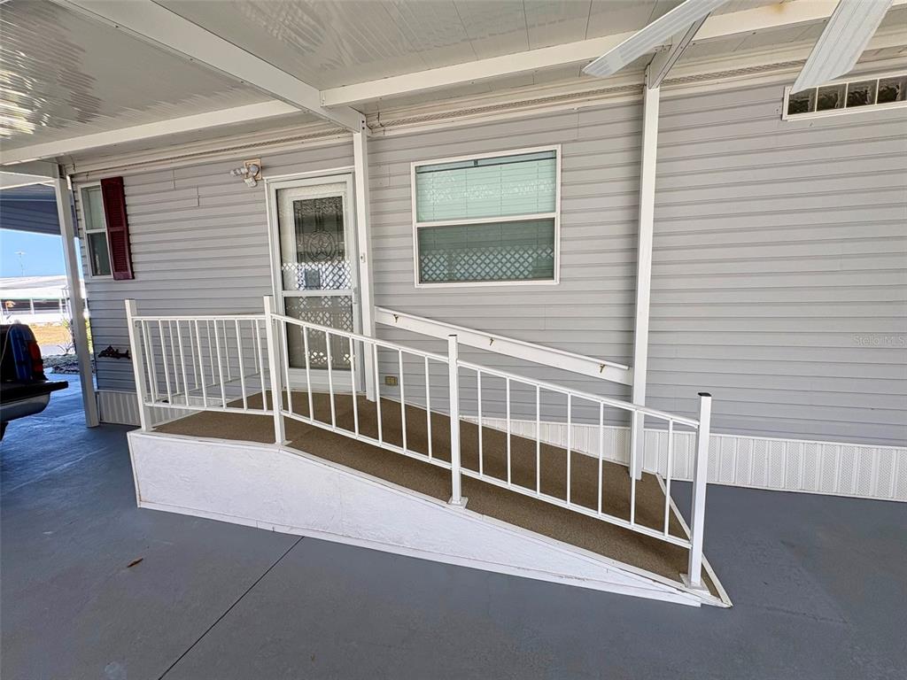 An exterior view of a manufactured home featuring a wheelchair ramp leading to the front door — 6086 SOUTHERN OAKS DRIVE SE, WINTER HAVEN, FL