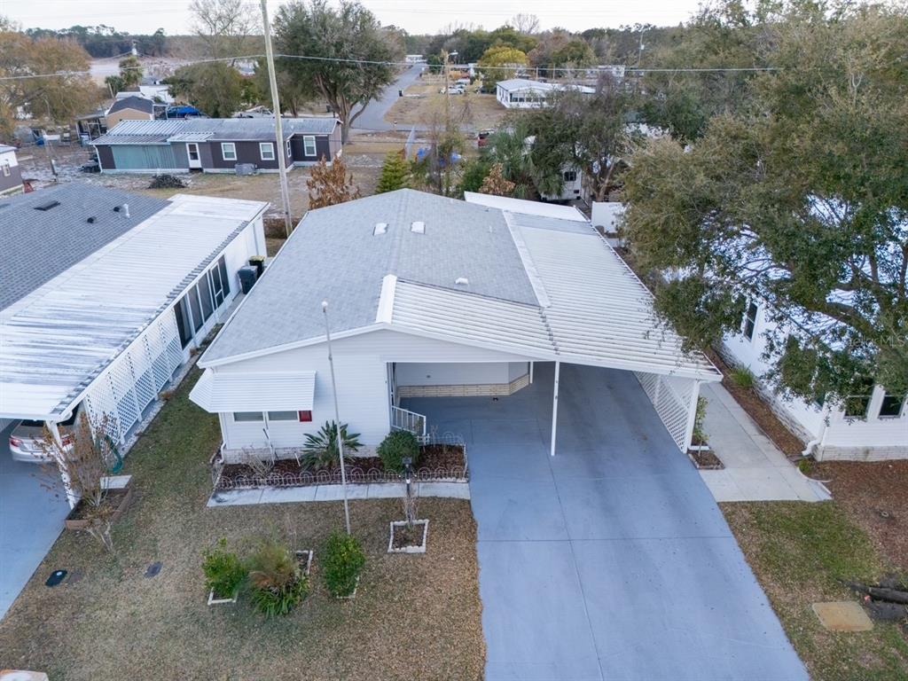An aerial view shows a white mobile home with a carport and a paved driveway — 6086 SOUTHERN OAKS DRIVE SE, WINTER HAVEN, FL
