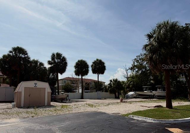 A gravel lot features a small storage shed, several palm trees, and parked boats — 5100 PROVIDENCE CIRCLE UNIT 3, NEW PORT RICHEY, FL