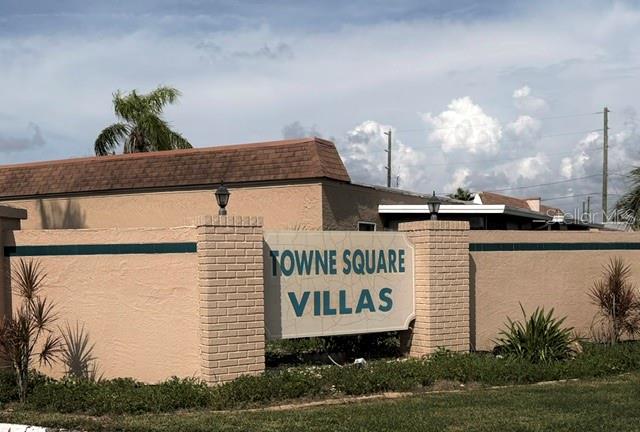 A beige stucco wall with a sign reading Towne Square Villas stands before a building — 5100 PROVIDENCE CIRCLE UNIT 3, NEW PORT RICHEY, FL