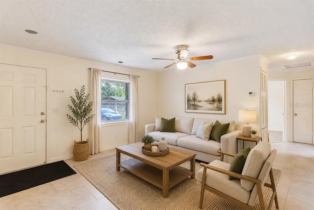 A living room features a beige sofa, wooden coffee table, armchair, and a ceiling fan — 1227 MERRITT STREET, ALTAMONTE SPRINGS, FL