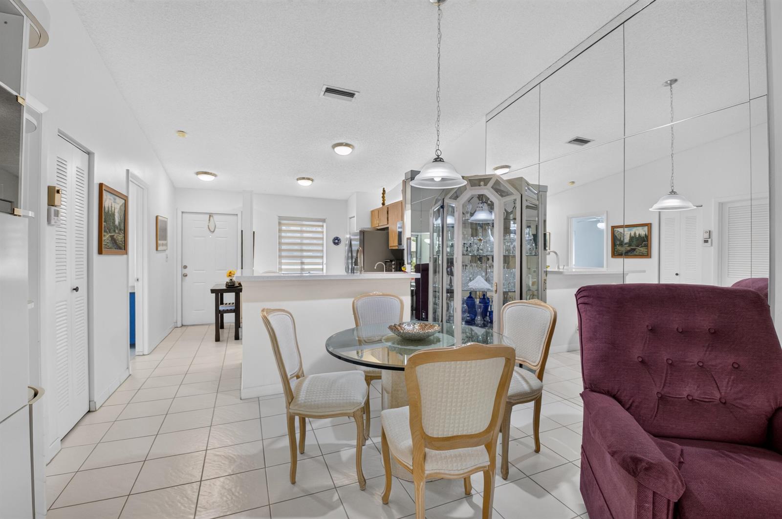 A dining area with a glass table, four chairs, and a mirrored wall — 18925 Argosy Drive # B, Boca Raton FL 33496, BOCA RATON, FL