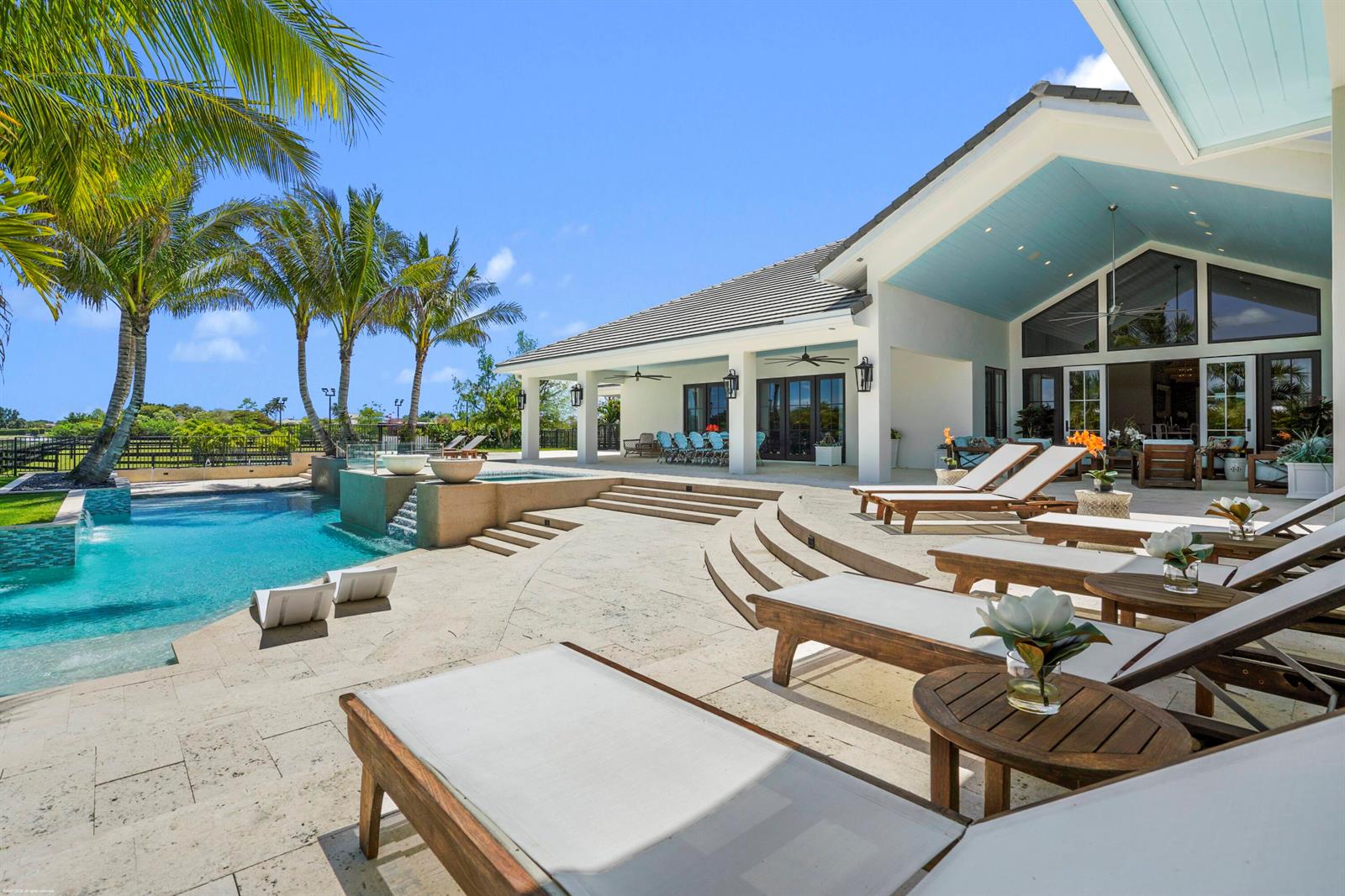 A swimming pool and patio area with lounge chairs outside a modern house — 14991 Palm Beach Point Boulevard, Wellington FL 33414, WELLINGTON, FL