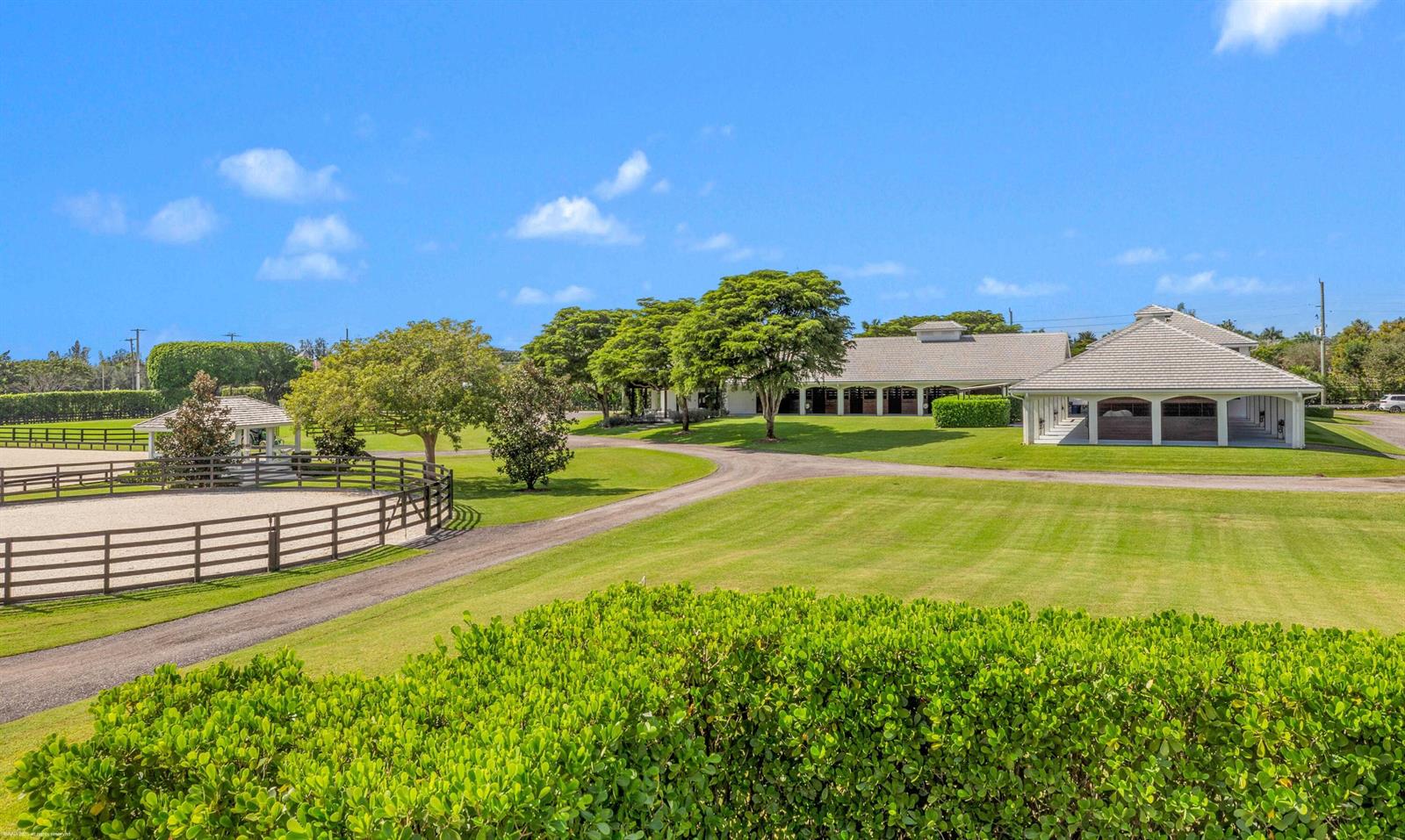 A gravel driveway leads to a horse stable complex with a fenced riding ring nearby — 14991 Palm Beach Point Boulevard, Wellington FL 33414, WELLINGTON, FL