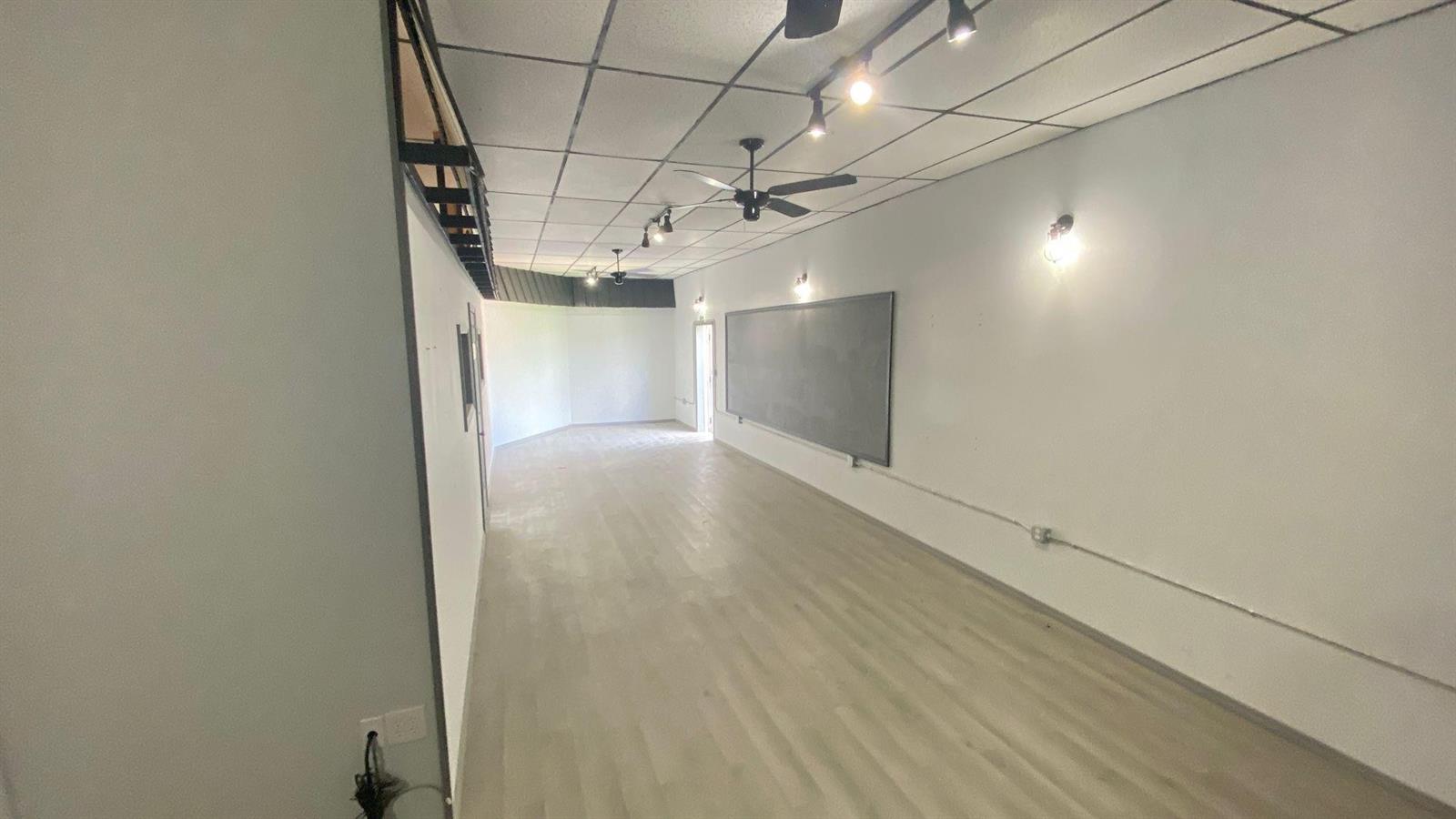 A long, empty room features light wood-look flooring, a drop ceiling, and a large chalkboard — 4650 US Highway 27, Sebring FL 33870, SEBRING, FL
