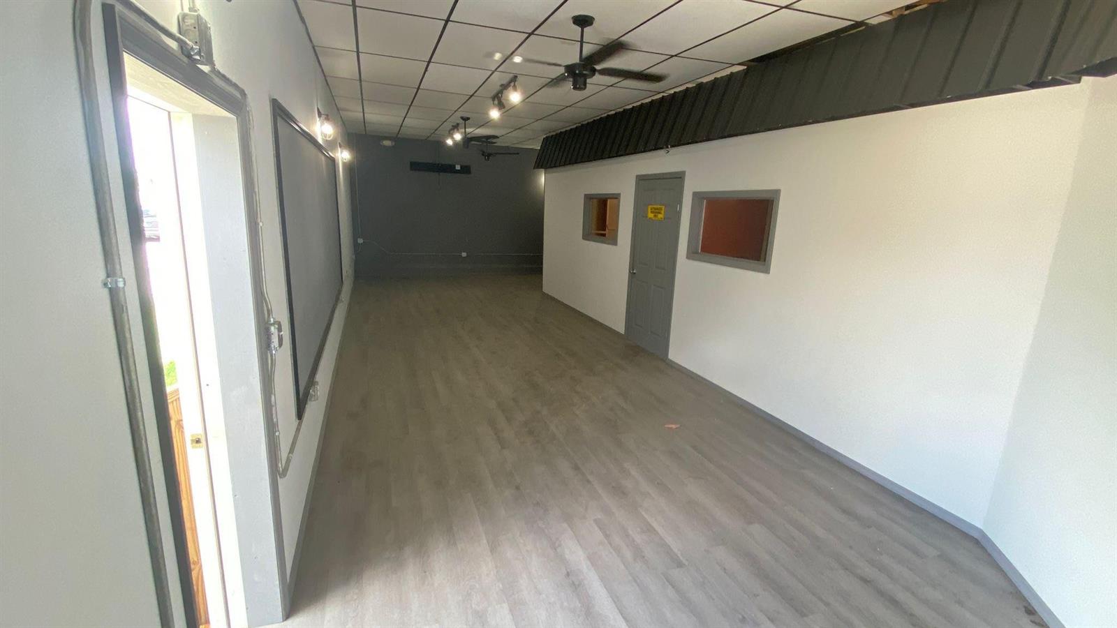 An empty commercial space features light wood-look flooring, a drop ceiling, and a gray door — 4650 US Highway 27, Sebring FL 33870, SEBRING, FL