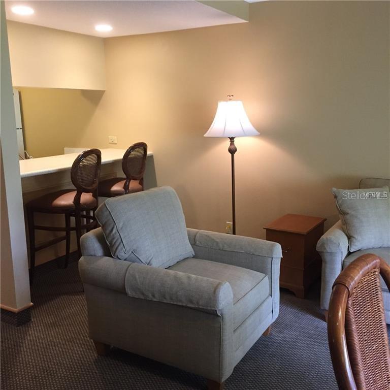 A living area features a breakfast bar with two chairs, a floor lamp, and seating — 36750 US HIGHWAY 19 N UNIT 2879, PALM HARBOR, FL