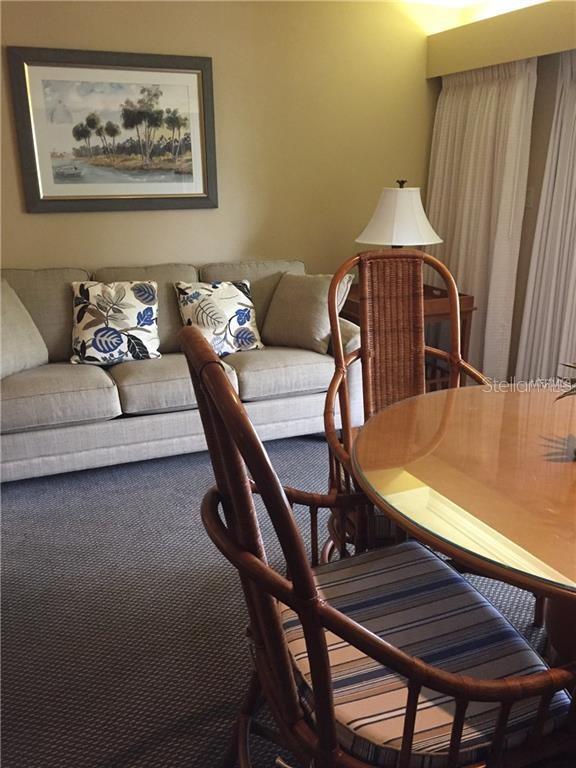 A living and dining area features a beige sofa, wicker chairs, and a glass-topped table — 36750 US HIGHWAY 19 N UNIT 2879, PALM HARBOR, FL