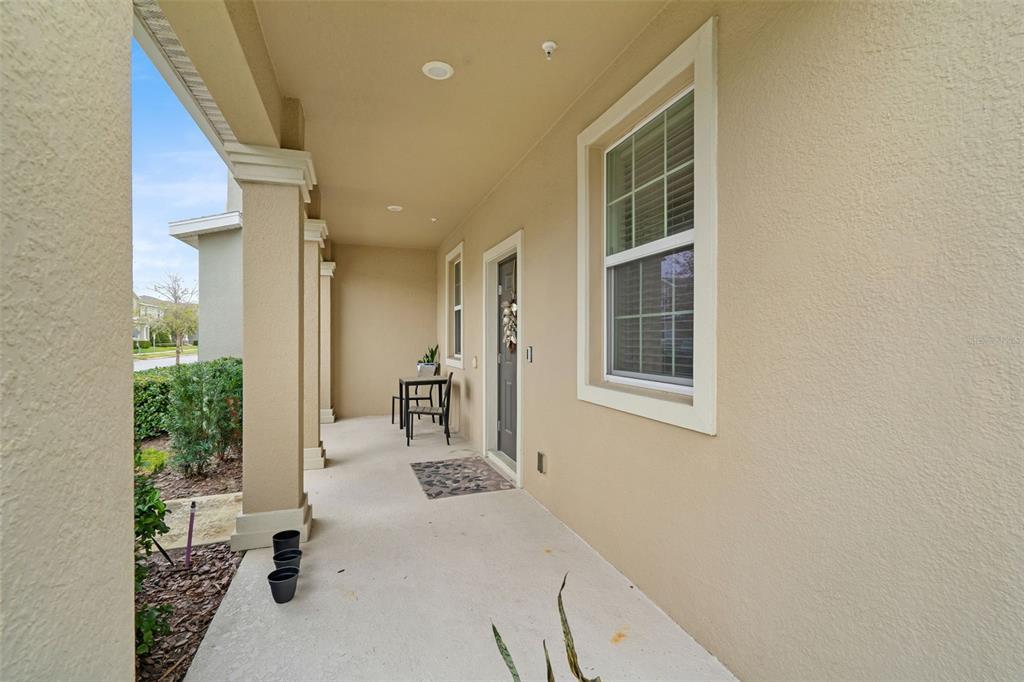 A covered front porch features beige stucco walls, a dark door, and a single window — 3105 AQUA VIRGO LOOP, ORLANDO, FL
