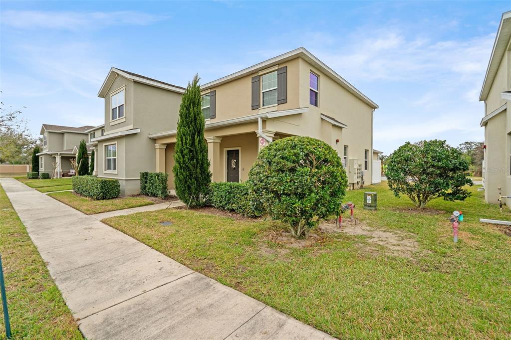 A two-story suburban house with a tan stucco exterior, a front porch, and landscaped yard — 3105 AQUA VIRGO LOOP, ORLANDO, FL