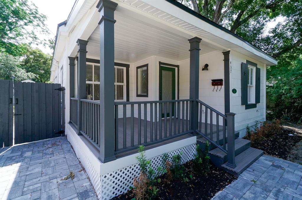 A white house with a dark gray porch, railings, and shutters sits beside a paved driveway — 437 N SHINE AVENUE, ORLANDO, FL