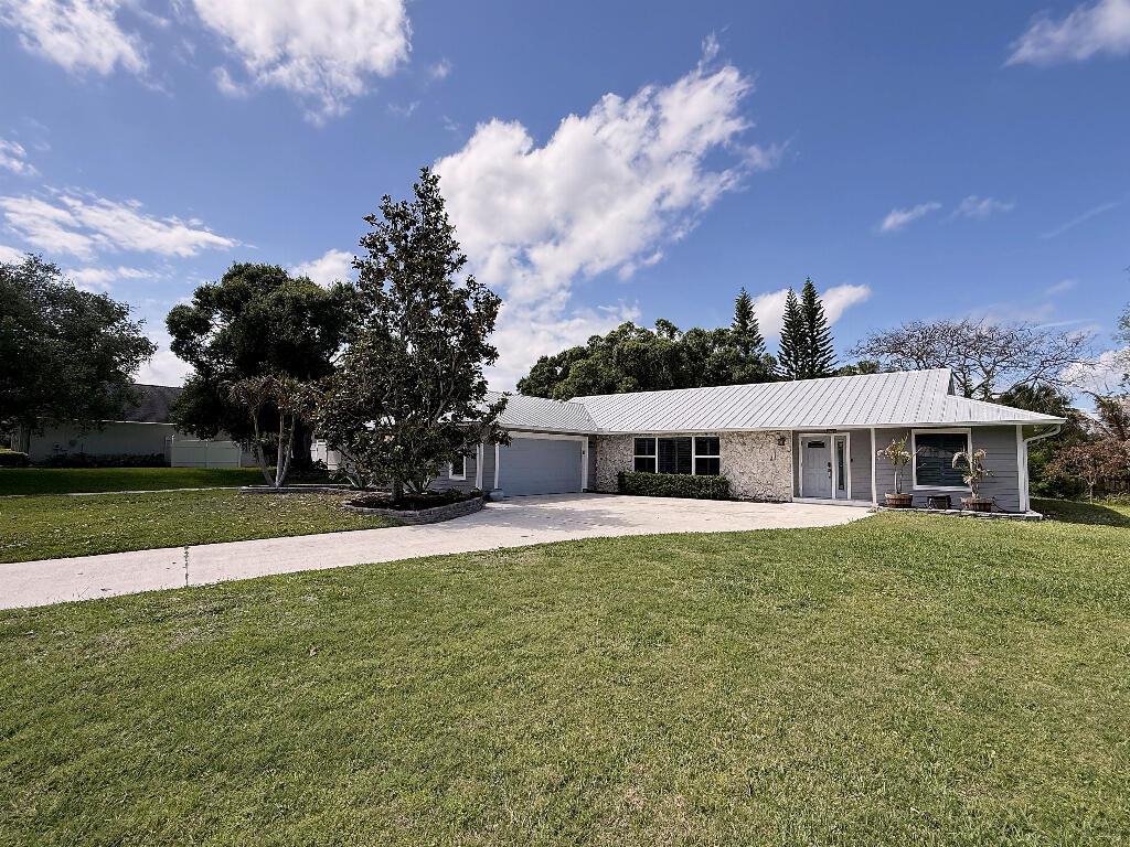 A single-story house with a metal roof, stone facade, and a concrete driveway — 2402 River Hammock Lane, Fort Pierce FL 34981, FORT PIERCE, FL