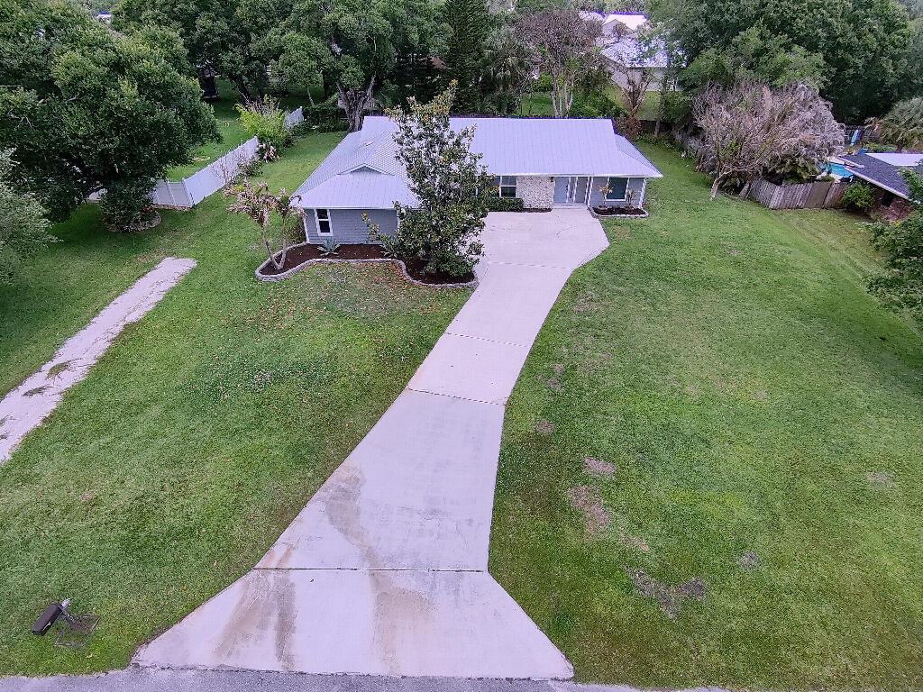 An aerial view of a single-story house with a metal roof and a concrete driveway — 2402 River Hammock Lane, Fort Pierce FL 34981, FORT PIERCE, FL