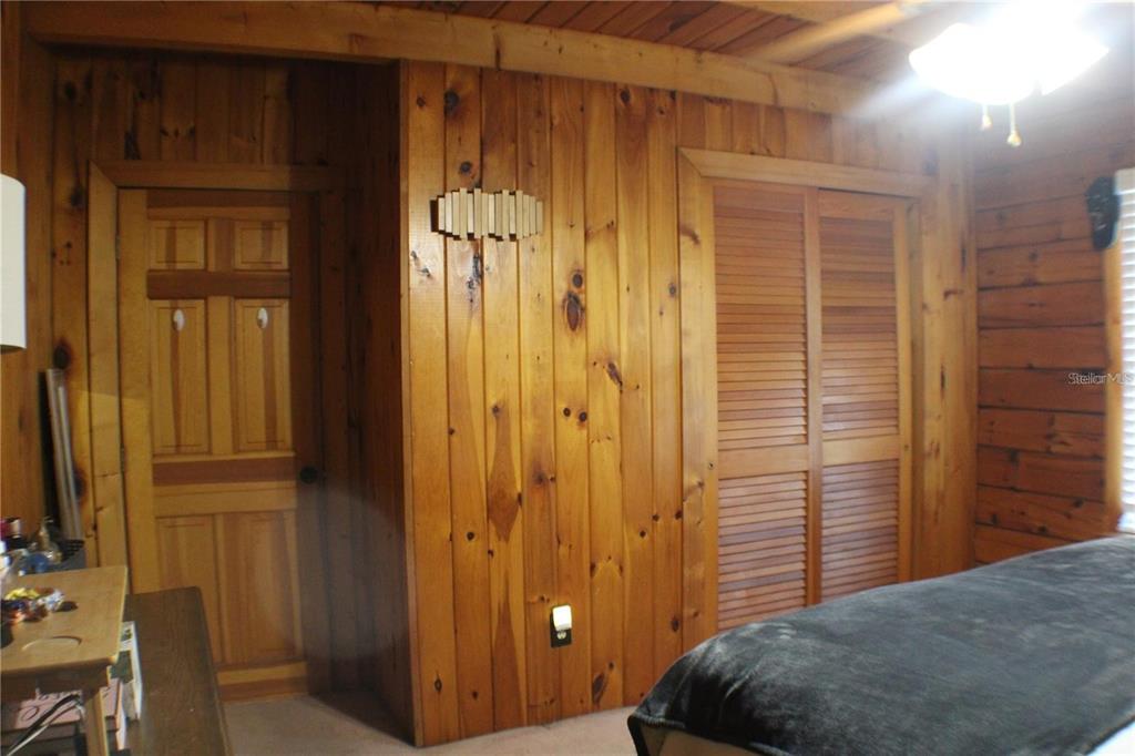 A bedroom features wood-paneled walls, a louvered closet door, and a wooden interior door — 3045 YORKSHIRE DRIVE, DELTONA, FL