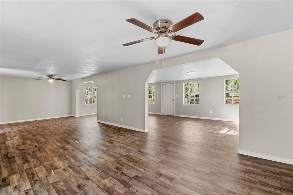 An open-concept living area features light gray walls, wood-look flooring, and two ceiling fans — 6111 KLARE DRIVE, KEYSTONE HEIGHTS, FL