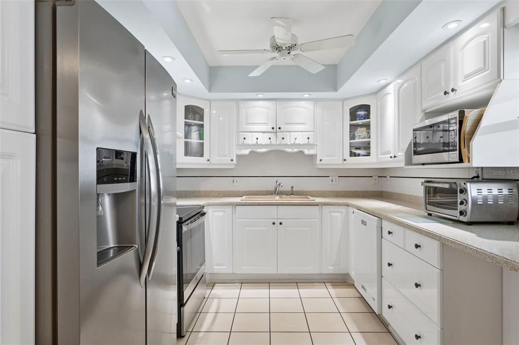 A kitchen with white cabinets, stainless steel appliances, tile flooring, and a ceiling fan — 5130 BRITTANY DRIVE S UNIT 1002, ST PETERSBURG, FL