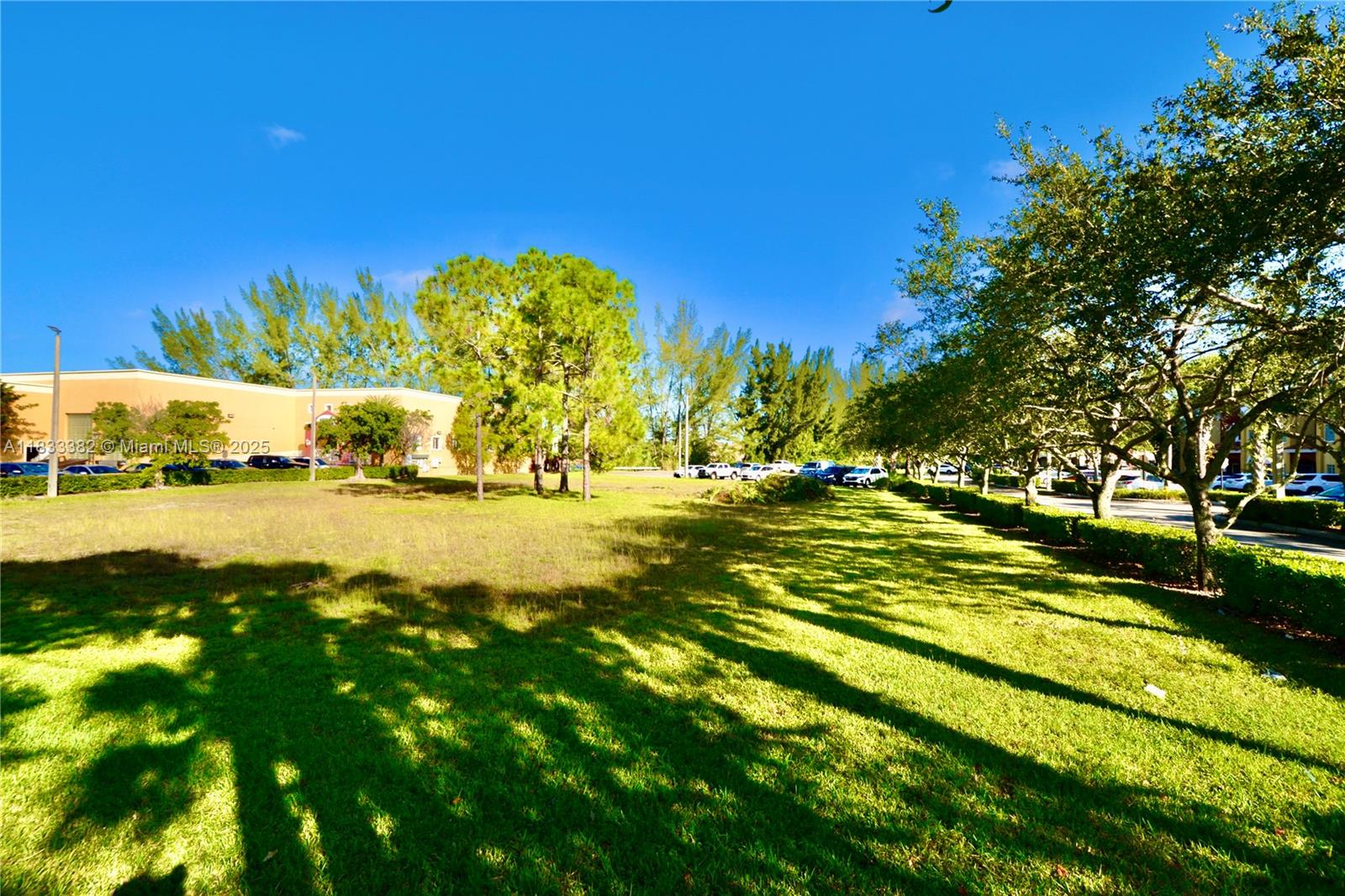 A grassy lawn sits in front of trees and a parking lot with several cars — 12957 SW 132nd Ter, Miami FL 33186, MIAMI, FL