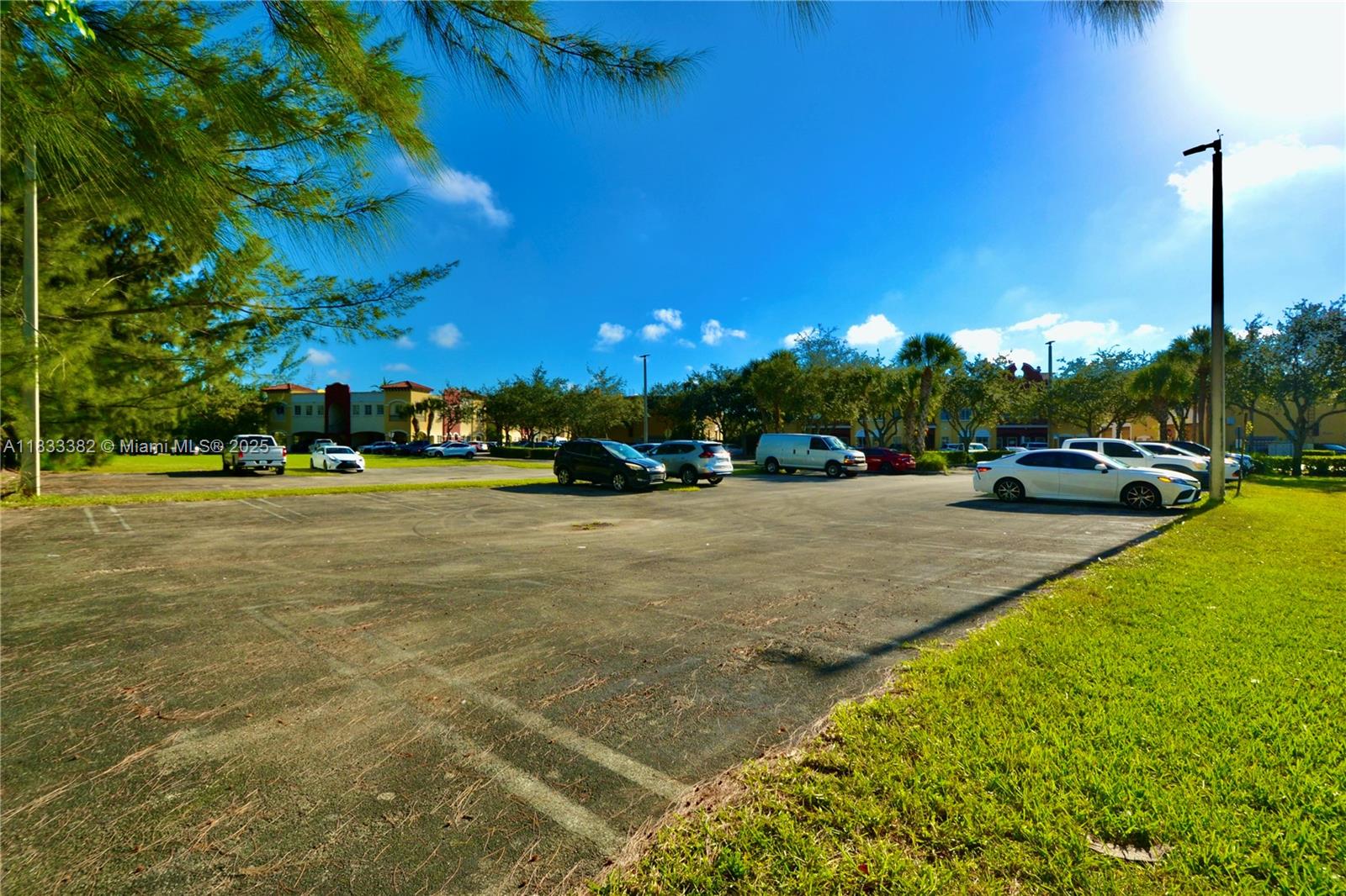 An outdoor parking lot with several parked cars under a clear blue sky — 12957 SW 132nd Ter, Miami FL 33186, MIAMI, FL