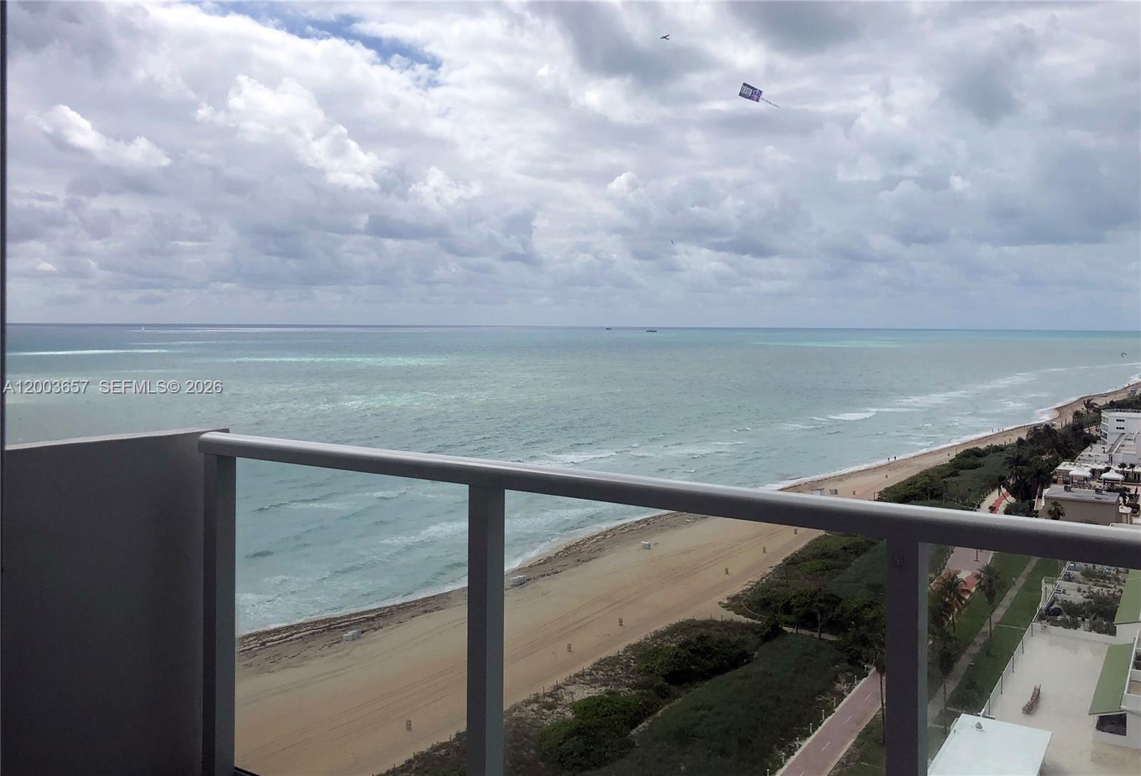 A high-angle view of a sandy beach and ocean from a balcony with railings — 5701 Collins Ave # 1714, Miami Beach FL 33140, MIAMI BEACH, FL