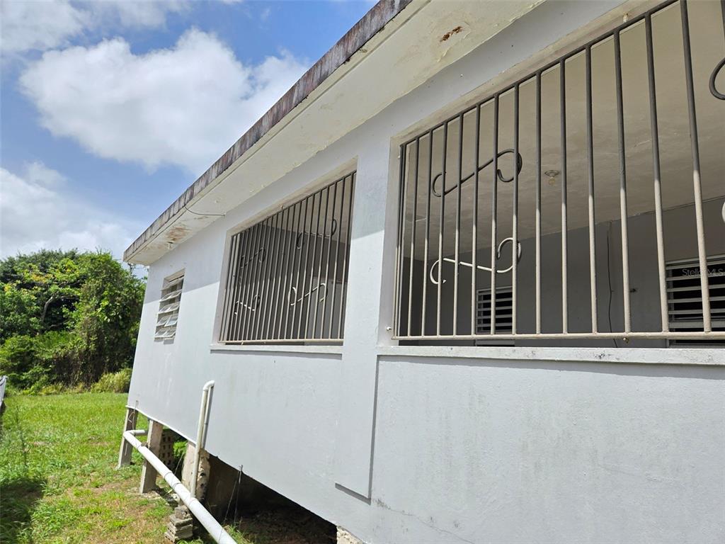 An exterior view of a white house with security bars on the windows — CALLE NAZARET SOLAR 403A COMUNIDAD SAN LUIS, AIBONITO, PR