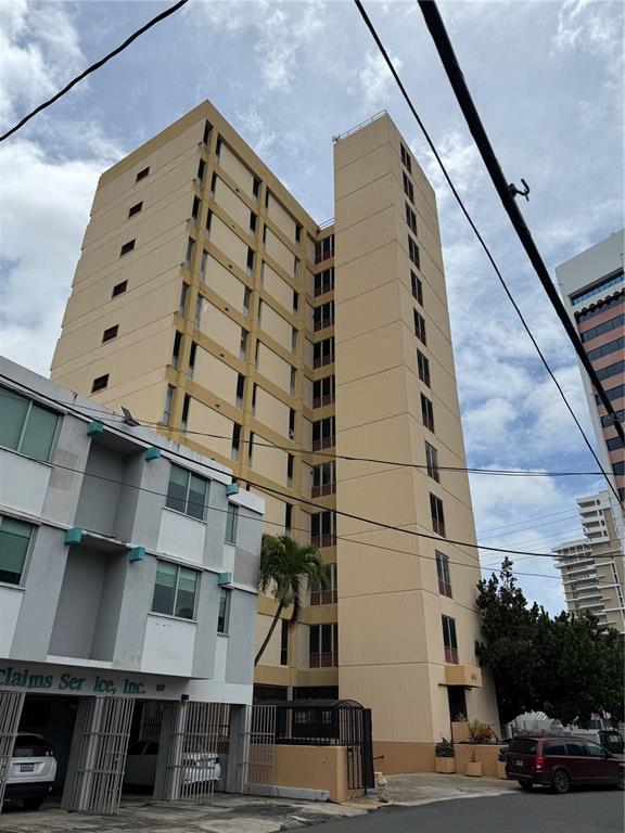 A tall, tan, multi-story apartment building stands behind a smaller, gray commercial structure — 414 MUÑOZ RIVERA AVENUE UNIT 6A & 6B, SAN JUAN, PR