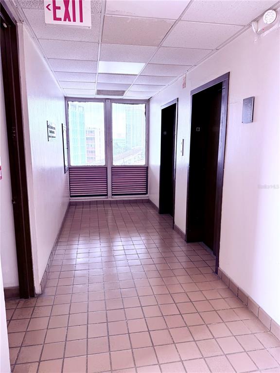 A hallway features tiled flooring, two elevator doors, and a window overlooking a city view — 414 MUÑOZ RIVERA AVENUE UNIT 6A & 6B, SAN JUAN, PR