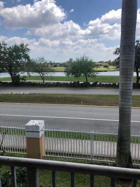 A view from a balcony overlooking a road, a grassy area, and a pond — 14340 SW 57th Ln # 204, Miami FL 33183, MIAMI, FL
