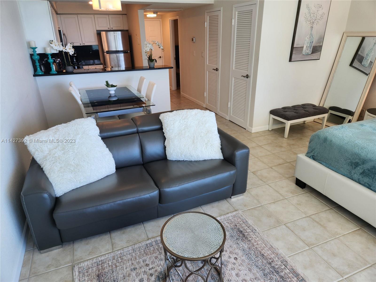 A living area with a dark leather sofa sits adjacent to a kitchen and dining space — 2501 S Ocean Dr # 512, Hollywood FL 33019, HOLLYWOOD, FL