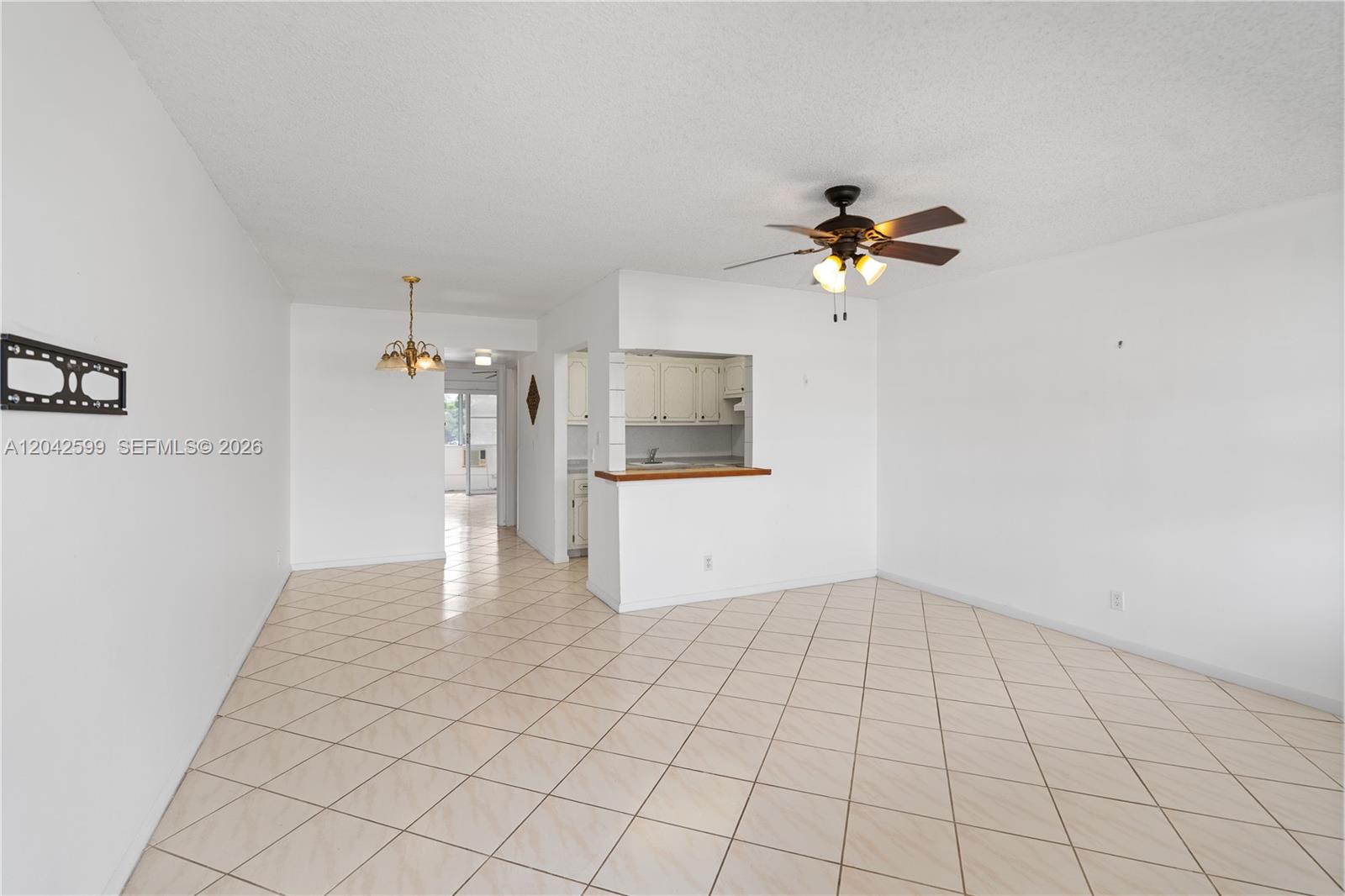 This living and dining area features white walls, tile flooring, and a kitchen pass-through window — 237 Camden J # 237, West Palm Beach FL 33417, WEST PALM BEACH, FL