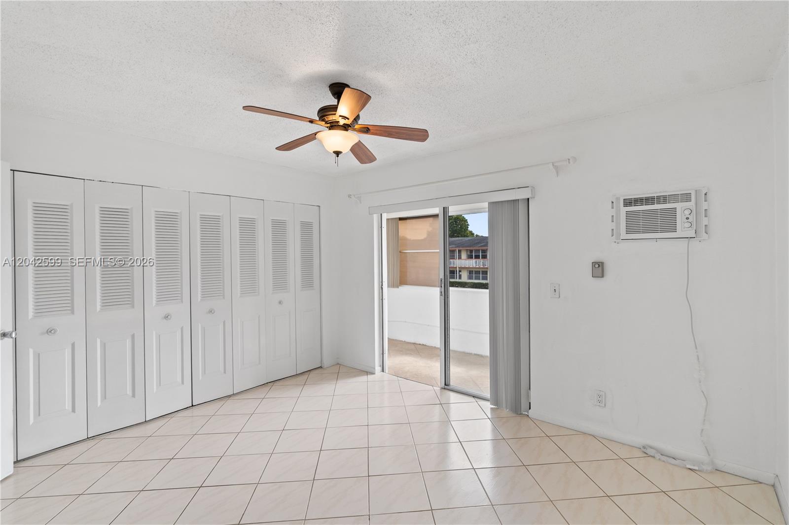 A room with white walls, tiled floors, a ceiling fan, sliding doors, and closet doors — 237 Camden J # 237, West Palm Beach FL 33417, WEST PALM BEACH, FL