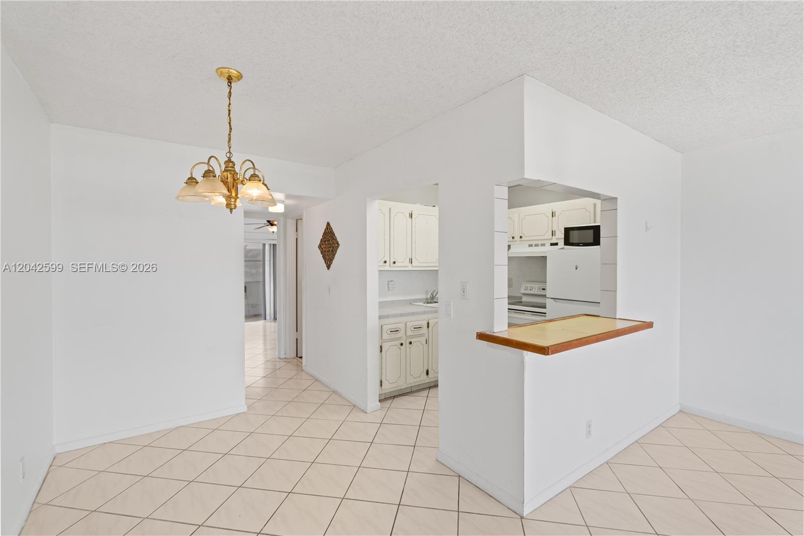 A dining area with a chandelier leads to a kitchen featuring a breakfast bar — 237 Camden J # 237, West Palm Beach FL 33417, WEST PALM BEACH, FL