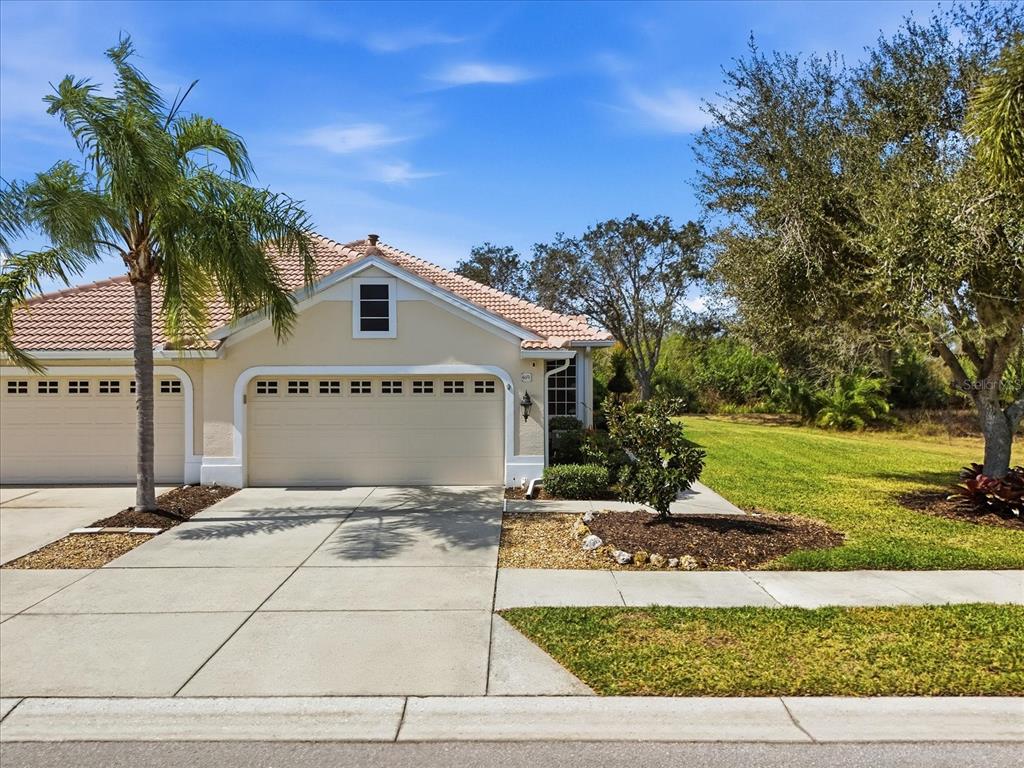 A beige single-story house with a tile roof, two-car garage, and a palm tree — 4693 WHISPERING OAKS DRIVE, NORTH PORT, FL