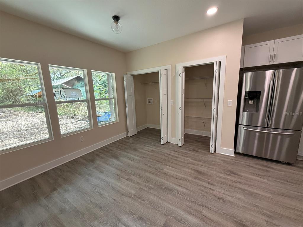 A room with wood-look flooring, two closet doors, and a stainless steel refrigerator — 4409 NW 31ST AVENUE, GAINESVILLE, FL
